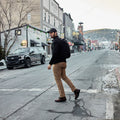 Man wearing GORUCK backpack crossing urban street in casual outdoor gear