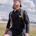 Man outdoors wearing GORUCK men's USA long sleeve performance half zip with rucksack