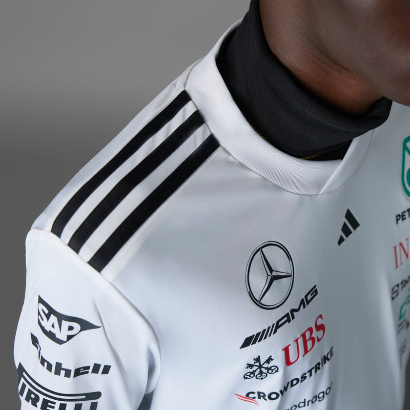 White replica jersey shoulder with black Adidas stripes, Mercedes emblem, and sponsor mark.