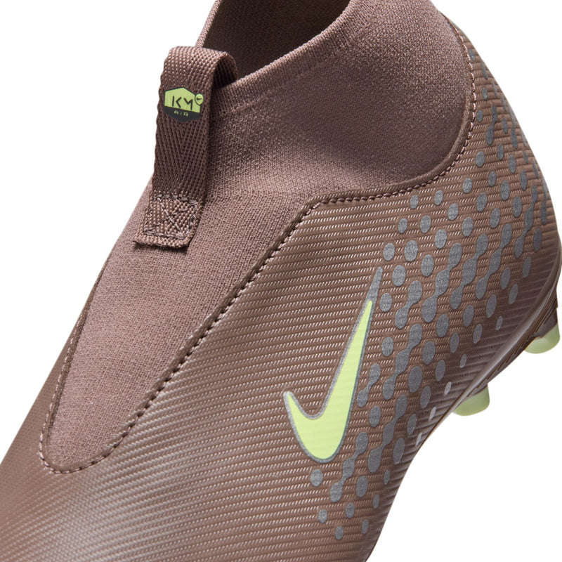 Youth soccer cleat close-up, plum upper with green swoosh and textured mesh detailing