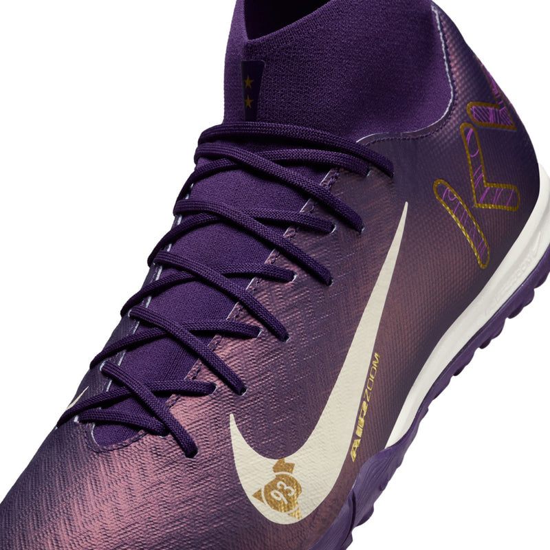 Men's purple TF football boot close-up, lace-up with pale ivory swoosh and gold accents