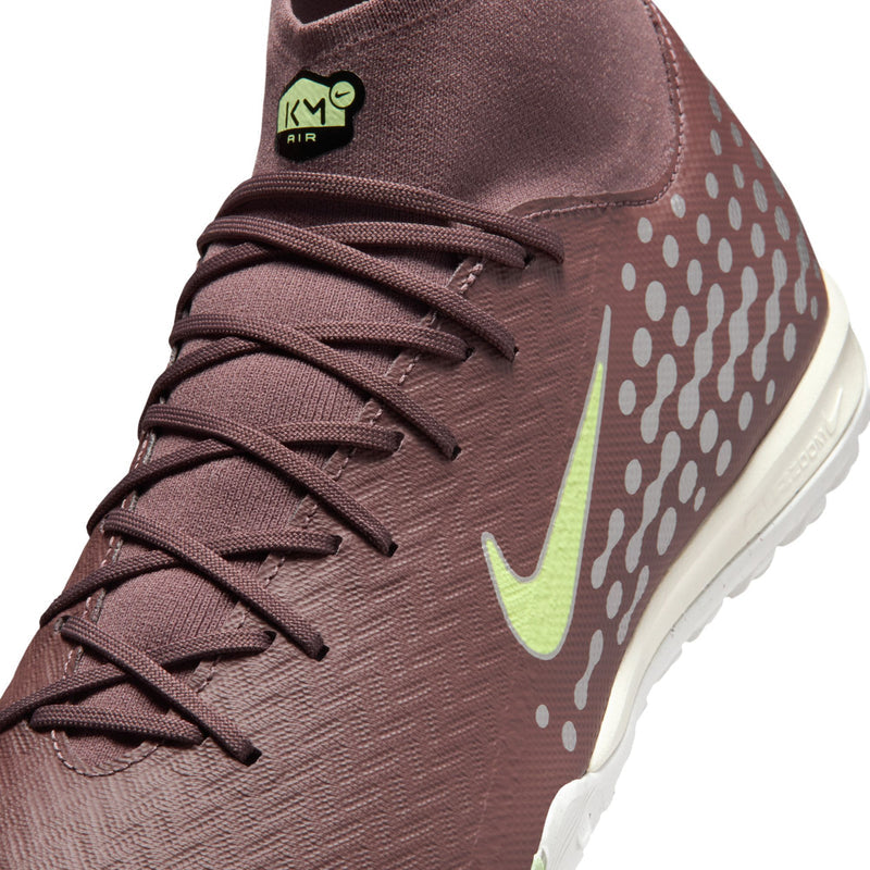 Close-up of plum soccer cleat laces, neon green swoosh, and KM Air tongue logo.