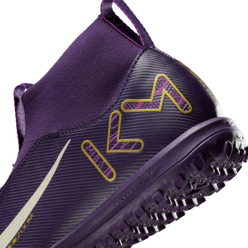 Purple youth TF soccer cleat close-up, gold graphic, white swoosh, turf studs outsole.