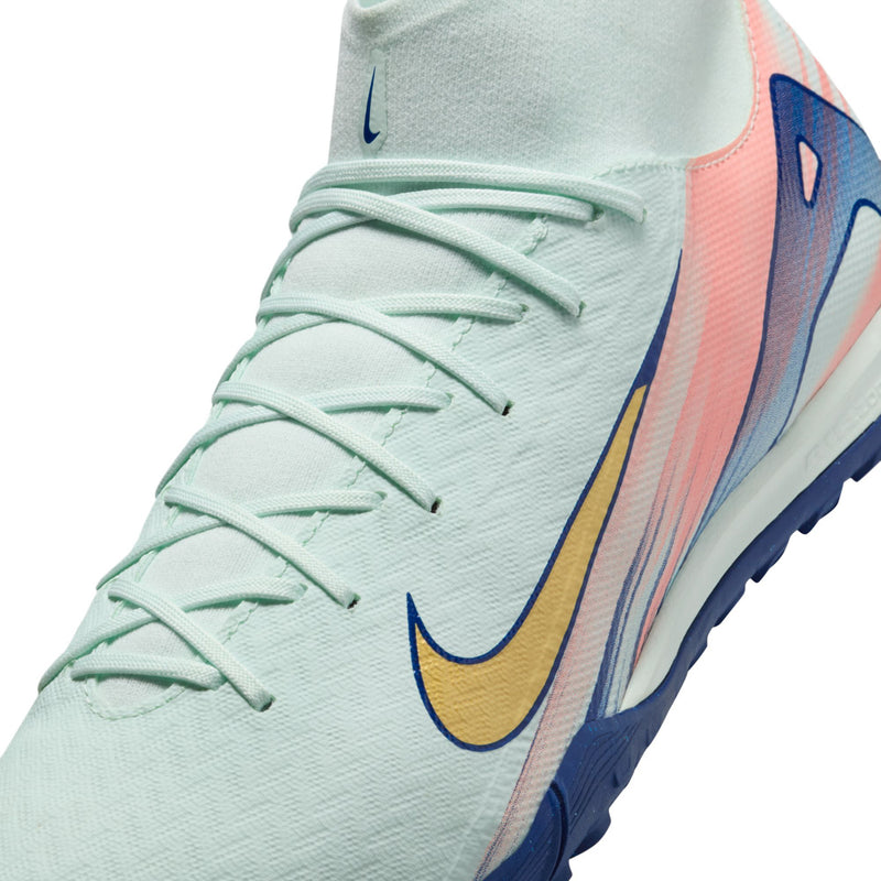 Men's turf cleat close-up with mint laces and gold swoosh on colorful side panel