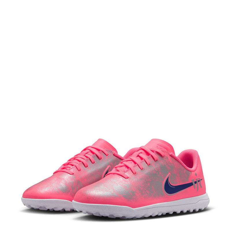 Pair of youth turf soccer cleats with bright pink uppers, dark blue swooshes, and gray soles.