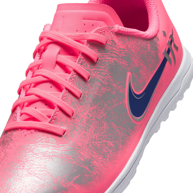 Close-up of youth pink turf cleat upper with textured pattern, lace loops, and dark blue swoosh.