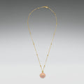 Gold necklace with a pink pendant on a gray background