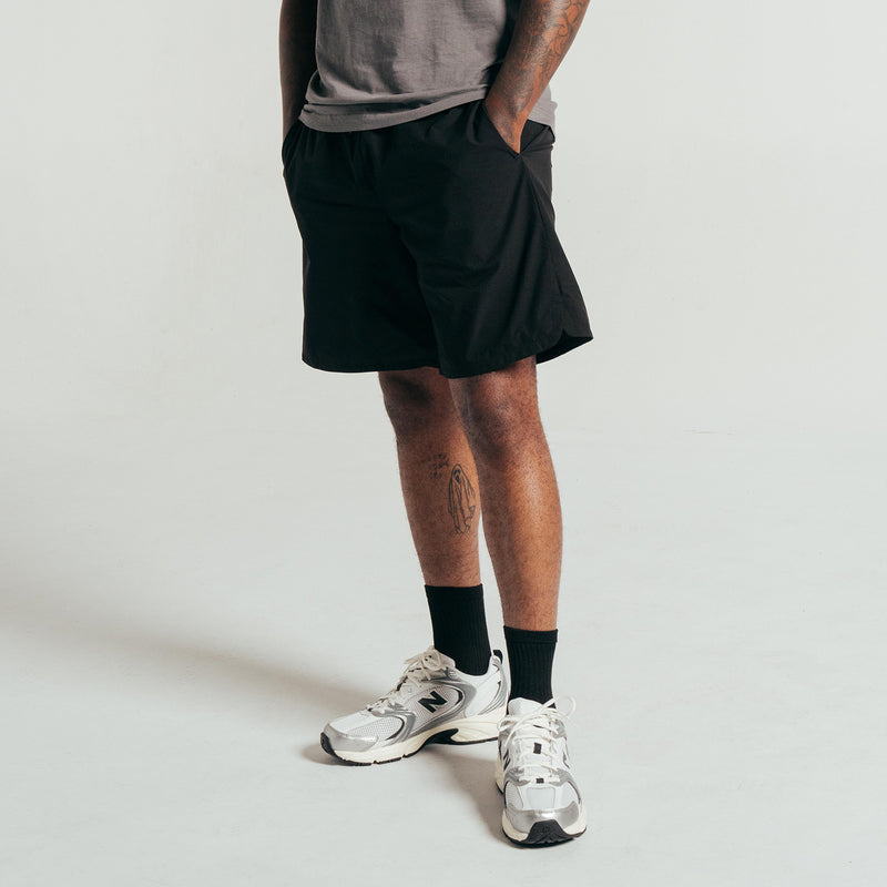 Black woven men's shorts on model, elastic waistband and side seams.