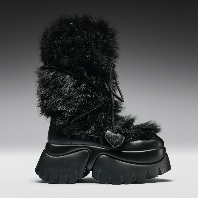 Black fur-trimmed boot with a heart detail on a gradient background