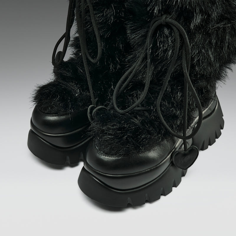 Black furry boots with thick soles on a light gray background