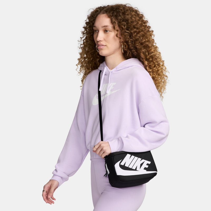 Mini crossbody bag worn cross-body on a person, black with white NIKE logo