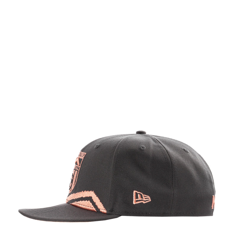 Dark grey snapback cap with coral mountain patch and small New Era logo.