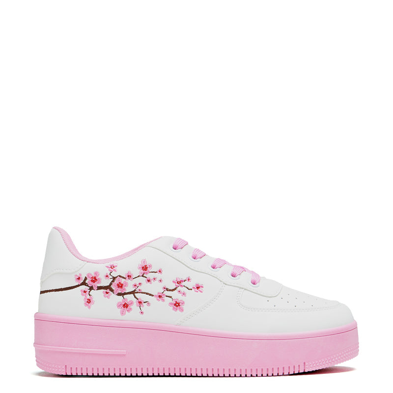 A pair of white platform trainers with pink floral embroidery on the top and a pink sole - Side View