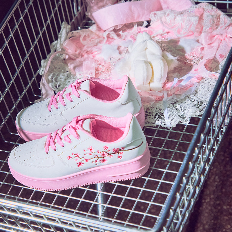 A pair of white platform trainers with pink floral embroidery on the top and a pink sole - Picture