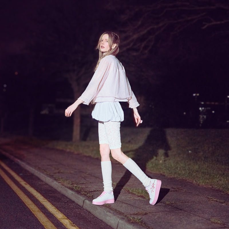 A pair of white platform trainers with pink floral embroidery on the top and a pink sole - Model 2