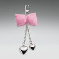 Pink bow keychain with heart-shaped pendants on a gray background