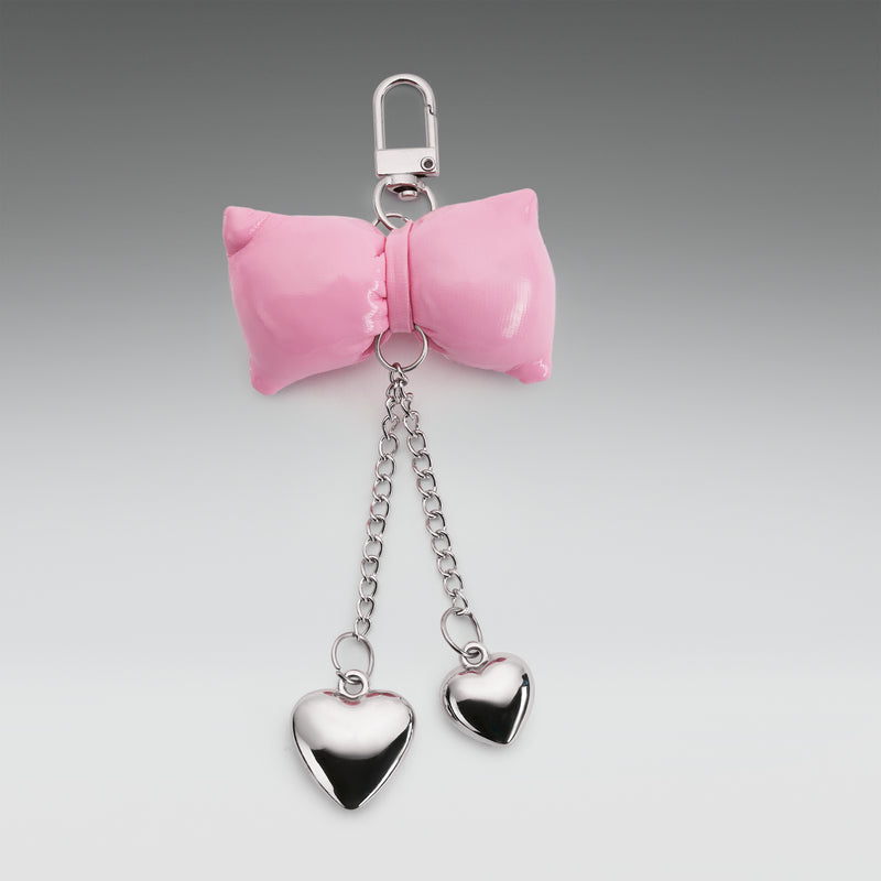 Pink bow keychain with heart-shaped pendants on a gray background