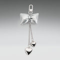 Silver bow keychain with heart-shaped pendants on a gray background
