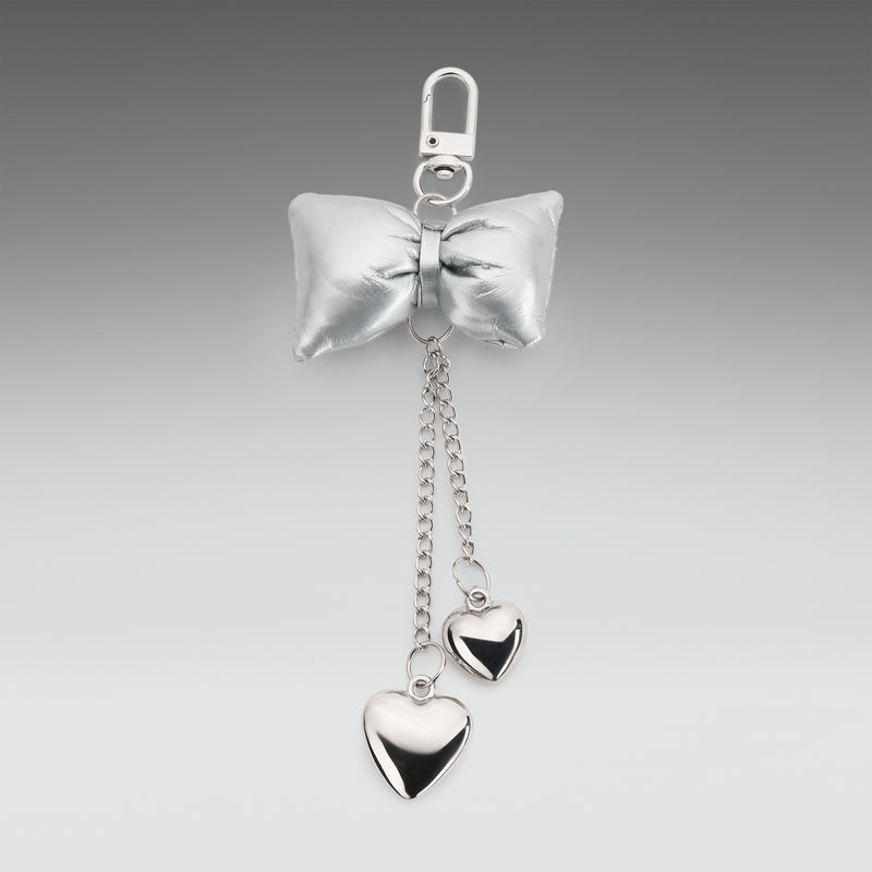 Silver bow keychain with heart-shaped pendants on a gray background