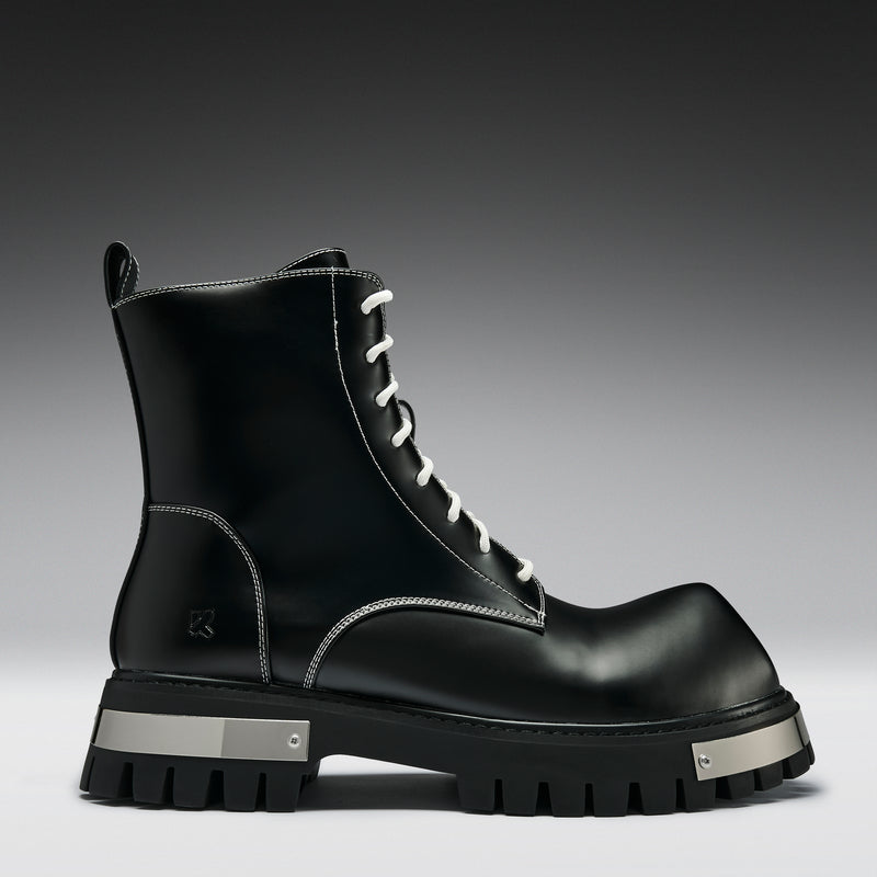 Black leather boot with white laces on a gray background