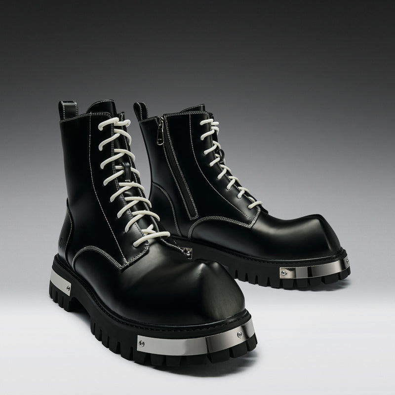 Pair of black leather boots with silver accents on a gradient background