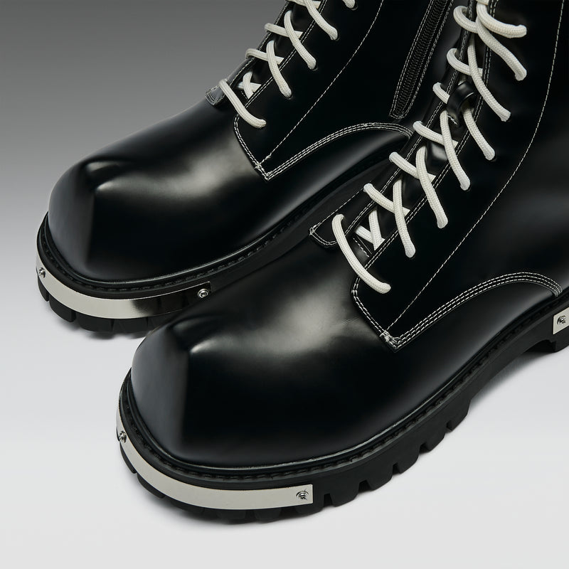 Black leather boots with white laces on a light gray background