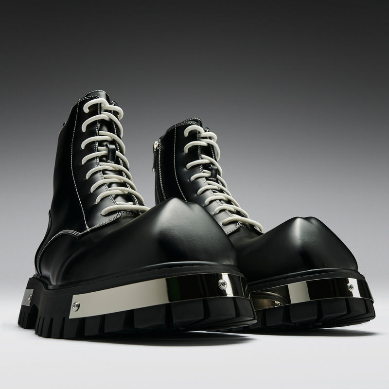 Black high-top boots with white laces on a gradient gray background