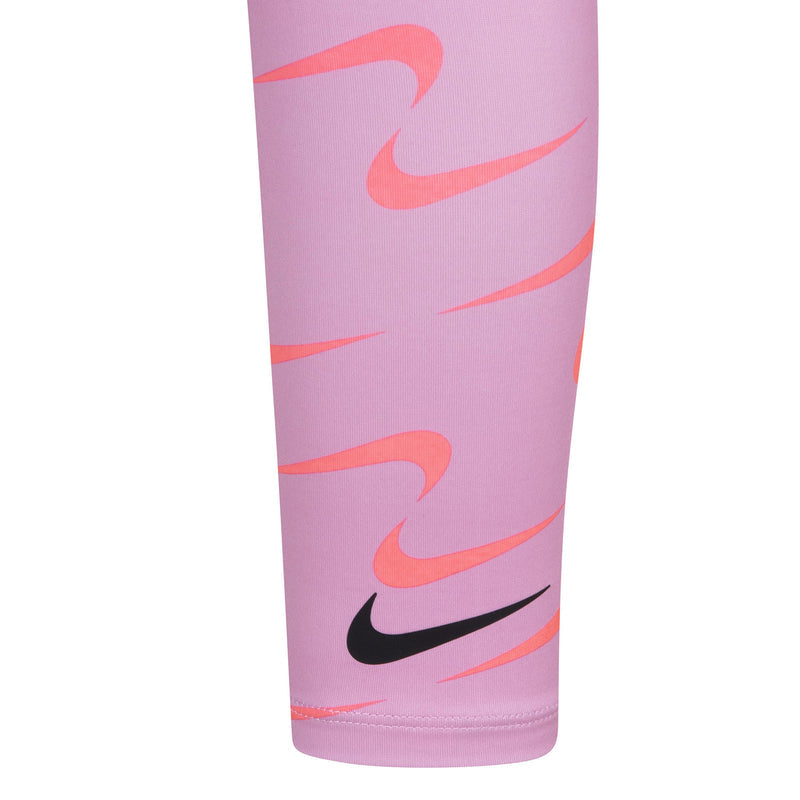 Pink leggings with repeating Nike swoosh pattern; cropped side close-up