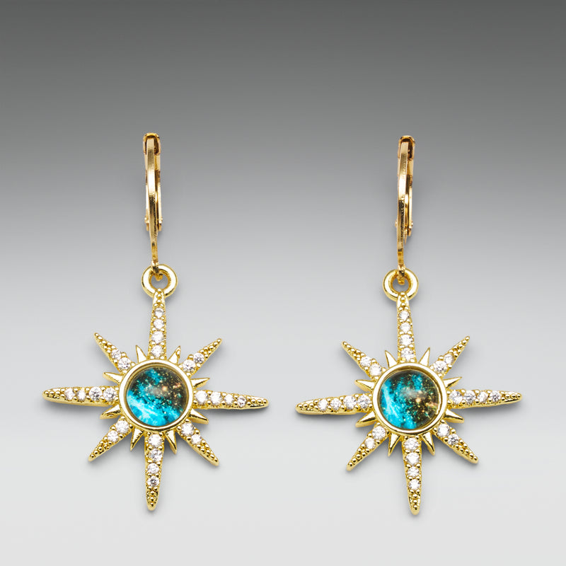 Gold sun-shaped earrings with turquoise centers on a gray background