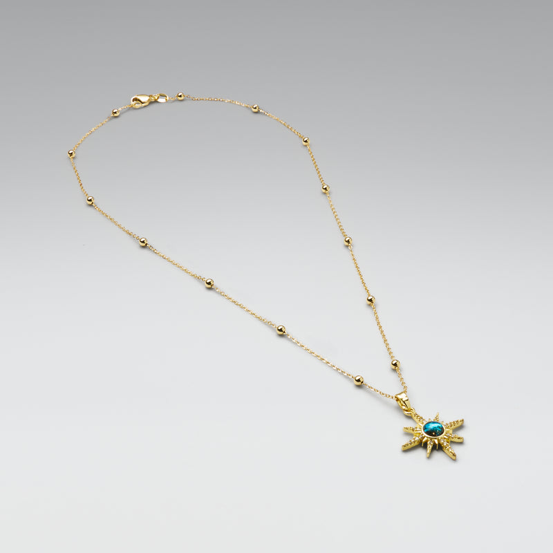Gold necklace with a star-shaped pendant on a gray background