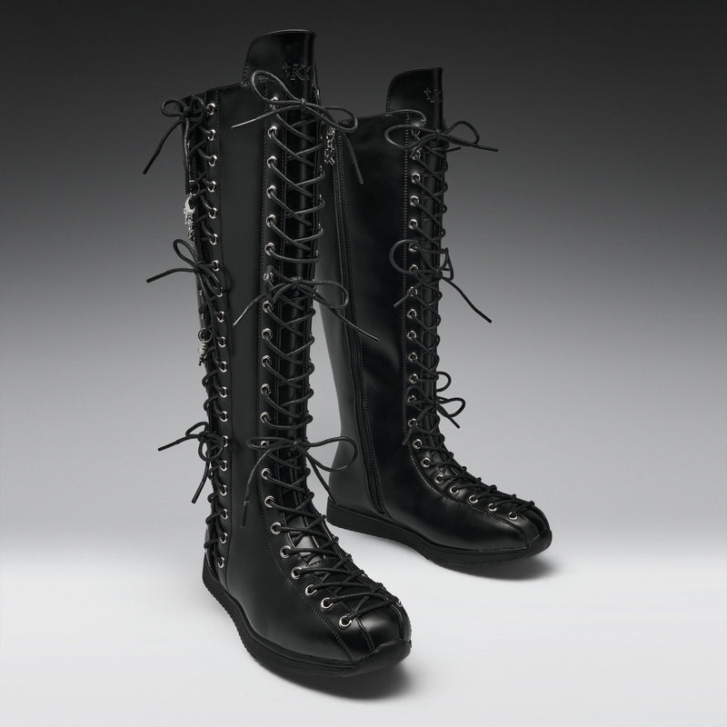 A pair of black leather knee-high lace-up boots with multiple decorative laces and silver-tone eyelets, photographed on a clean gray studio background.