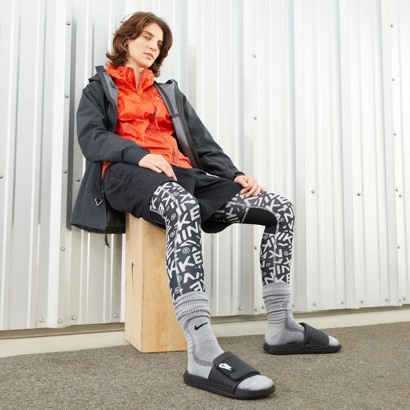 Women’s black Nike slide sandals with patterned leggings and gray socks