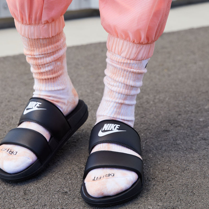 Women's black Nike slide sandals on feet with striped socks