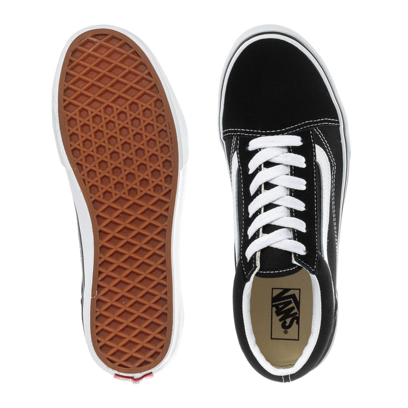 Black Vans youth sneakers with white laces; underside outsole shows tan waffle tread.