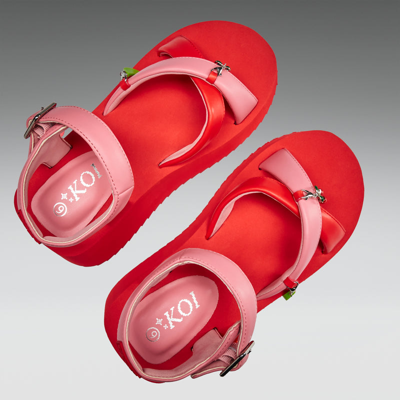Red sandals with pink straps on a gray background