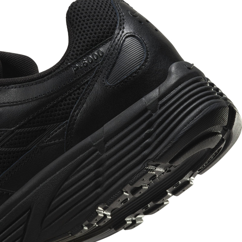 Men's black Nike running shoe close-up, ridged midsole and textured side panel