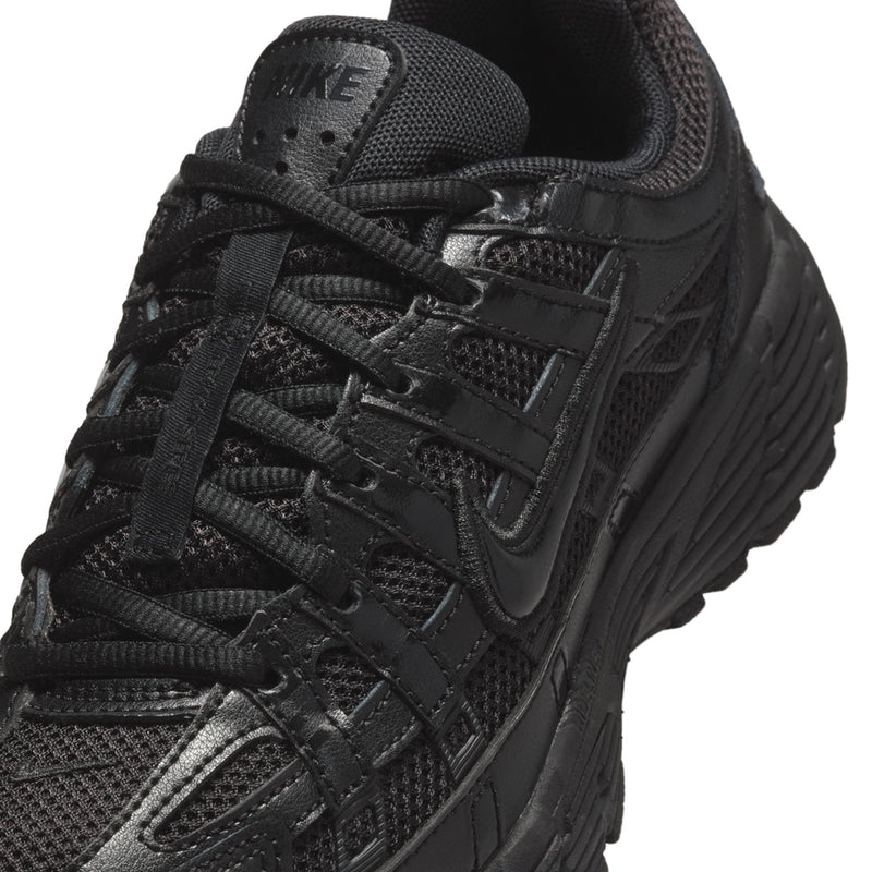 Black Nike sneakers close-up, laces, mesh panels, and stitched overlays