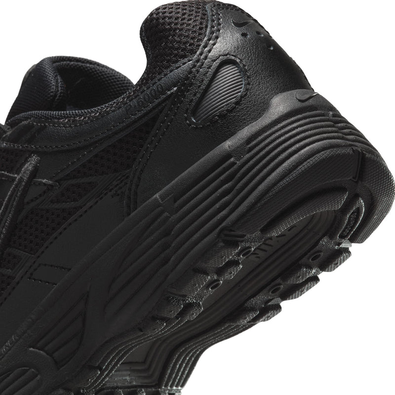 Black Nike sneaker close-up, textured toe and ribbed midsole with tread