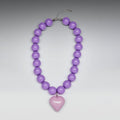 Purple beaded necklace with a heart-shaped pendant on a gray background