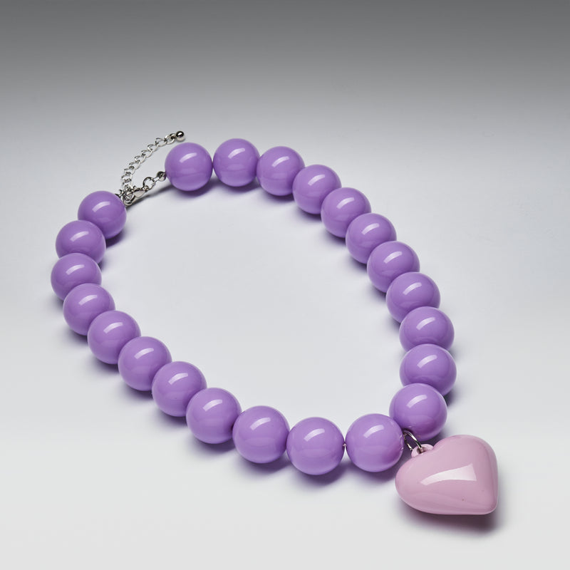 Purple beaded necklace with a heart-shaped pendant on a gray background