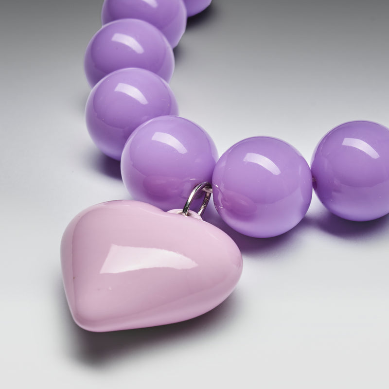 Necklace with purple beads and a heart-shaped pendant on a light gray background