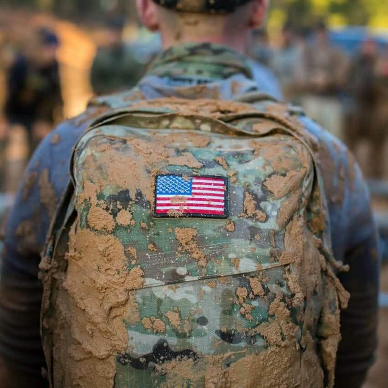 GORUCK camouflage rucksack with American flag patch, muddy from outdoor rucking event