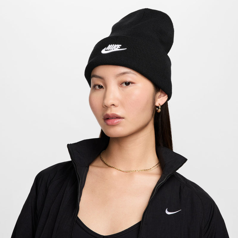 Black Nike beanie with folded cuff, white swoosh logo, worn by a model.