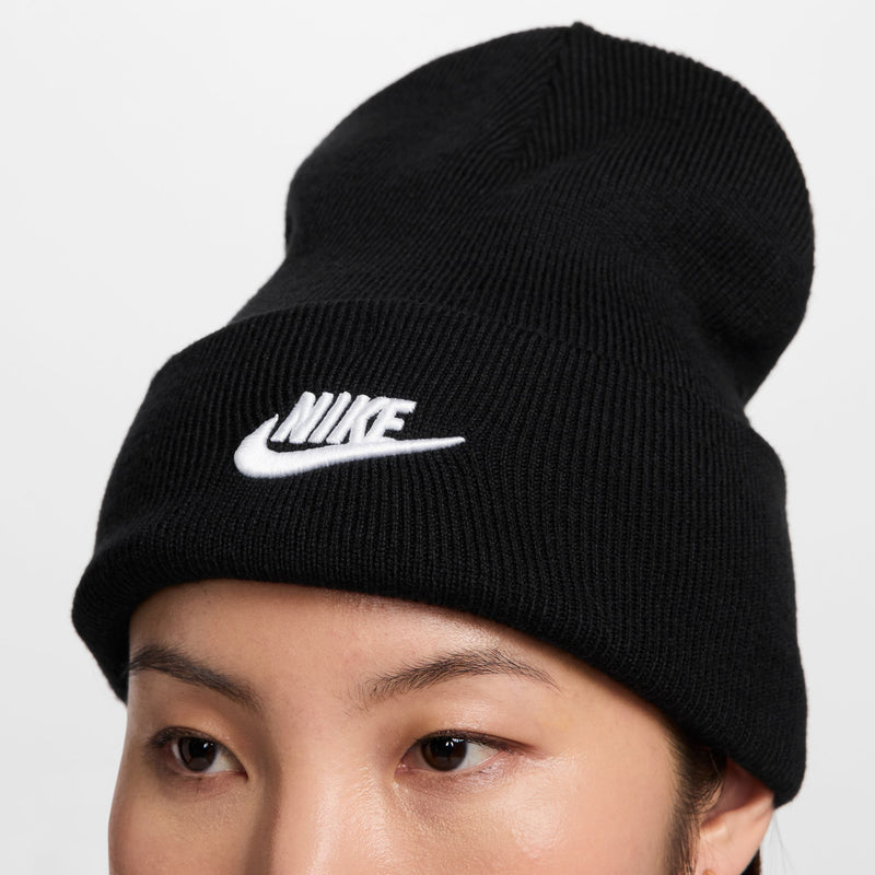 Black Nike knit beanie with white swoosh logo on the cuff, close-up view.