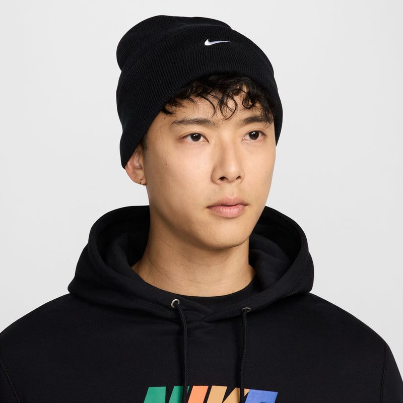 Black knit beanie with white Nike swoosh logo, worn by model