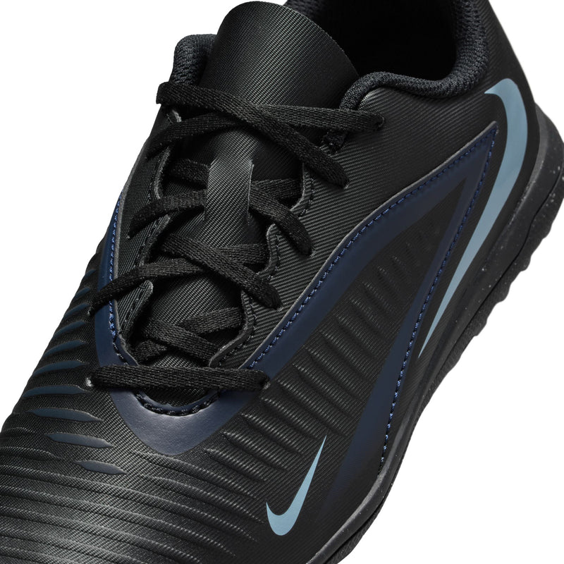 Youth soccer turf shoe close-up, black mesh upper with blue stripes and Nike logo