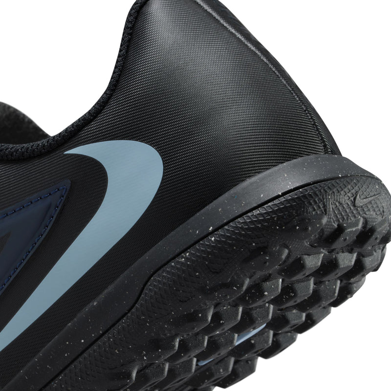 Youth soccer turf shoe close-up, black toe with textured rubber outsole and blue swoosh