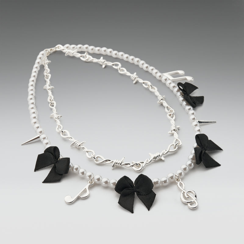 Necklace with black bow and treble clef charms on a gray background