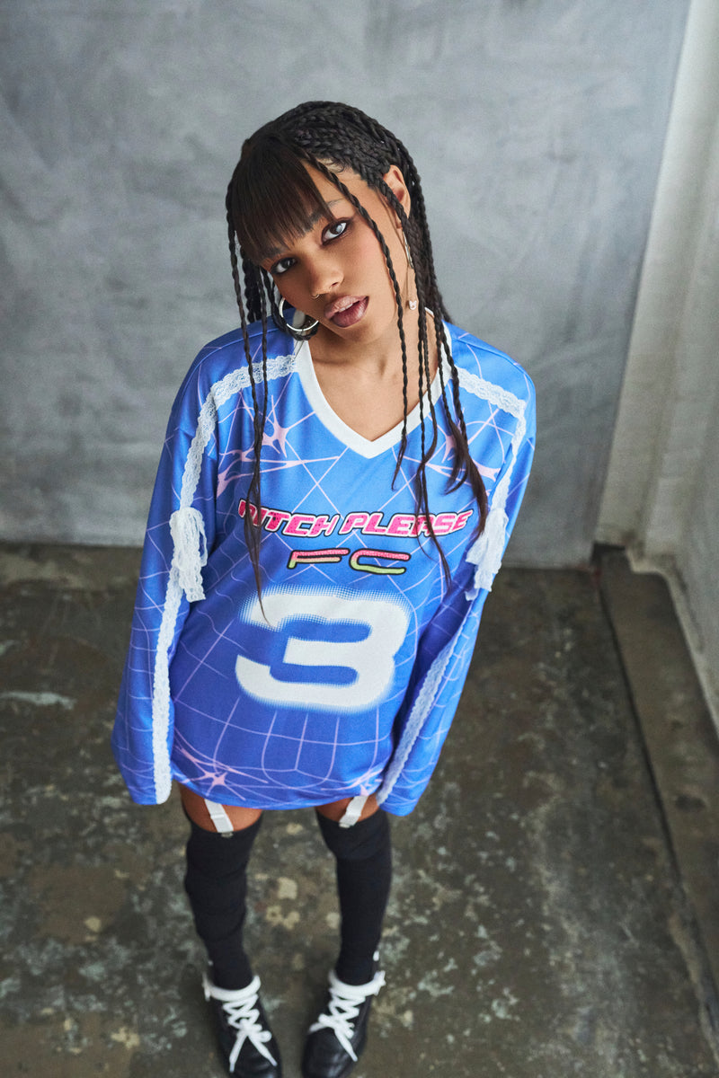 Person wearing a blue sports jersey with number 3 against a gray wall.