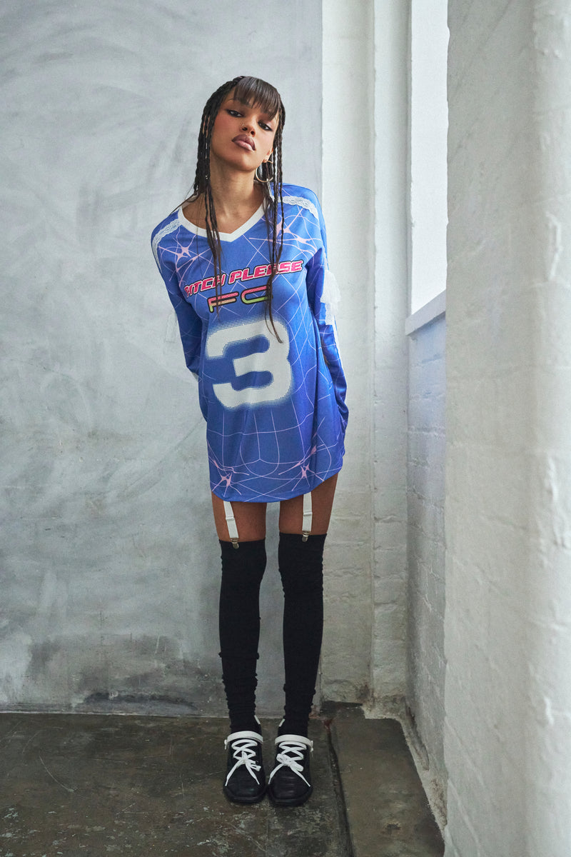 Person wearing a blue sports jersey with number 3 against a gray wall.